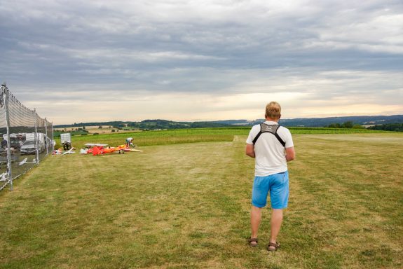 Beste Bedingungen Mann steht auf Flugplatz und fliegt mit seinem Modell