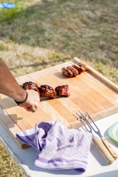 Eben noch auf dem Grill und jetzt schon auf dem Teller Person schneidet Fleisch, dass eben frisch vom Grill kam